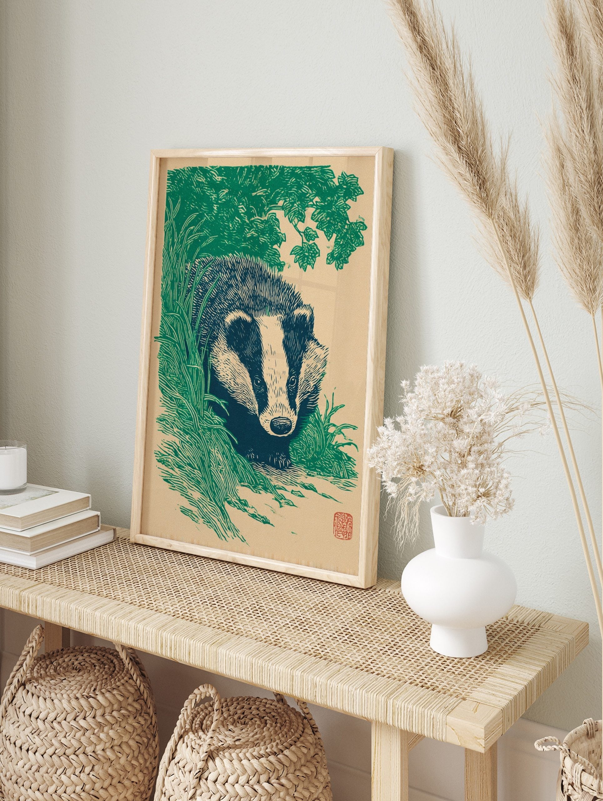 Illustrative green and beige badger animal art print emerging from foliage in a woodcut style, in an alternate framed mockup