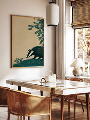 Illustrative dark teal badger with white stripes sniffing grass, textured beige background, and, in a styled room mockup