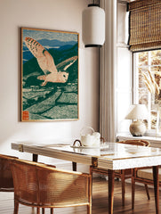 Barn owl in flight over terraced fields and mountains, green, blue, beige woodblock print style, in a styled room mockup