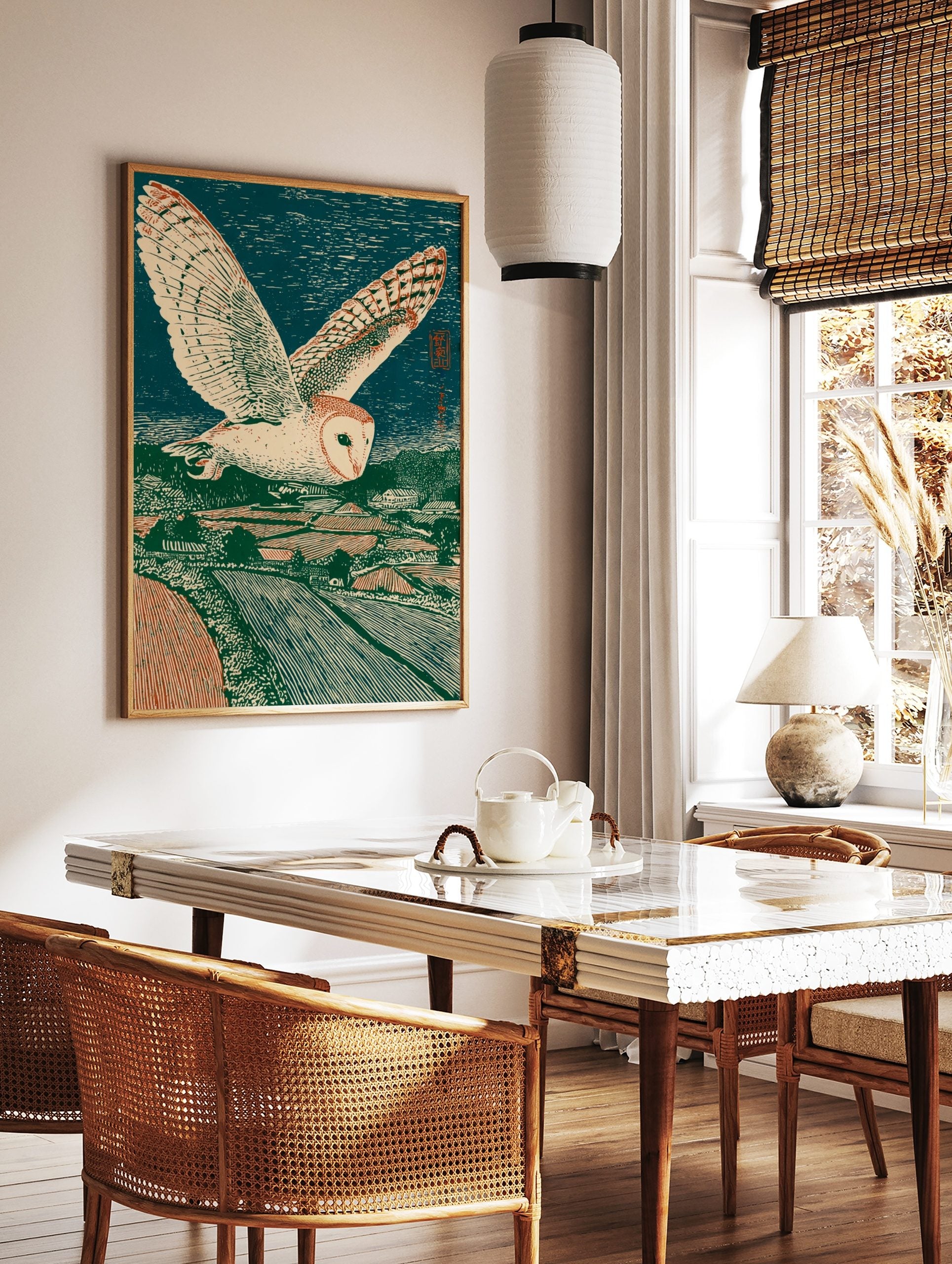 Japanese woodblock print of a barn owl flying over a green and red rural landscape under a dark, in a styled room mockup