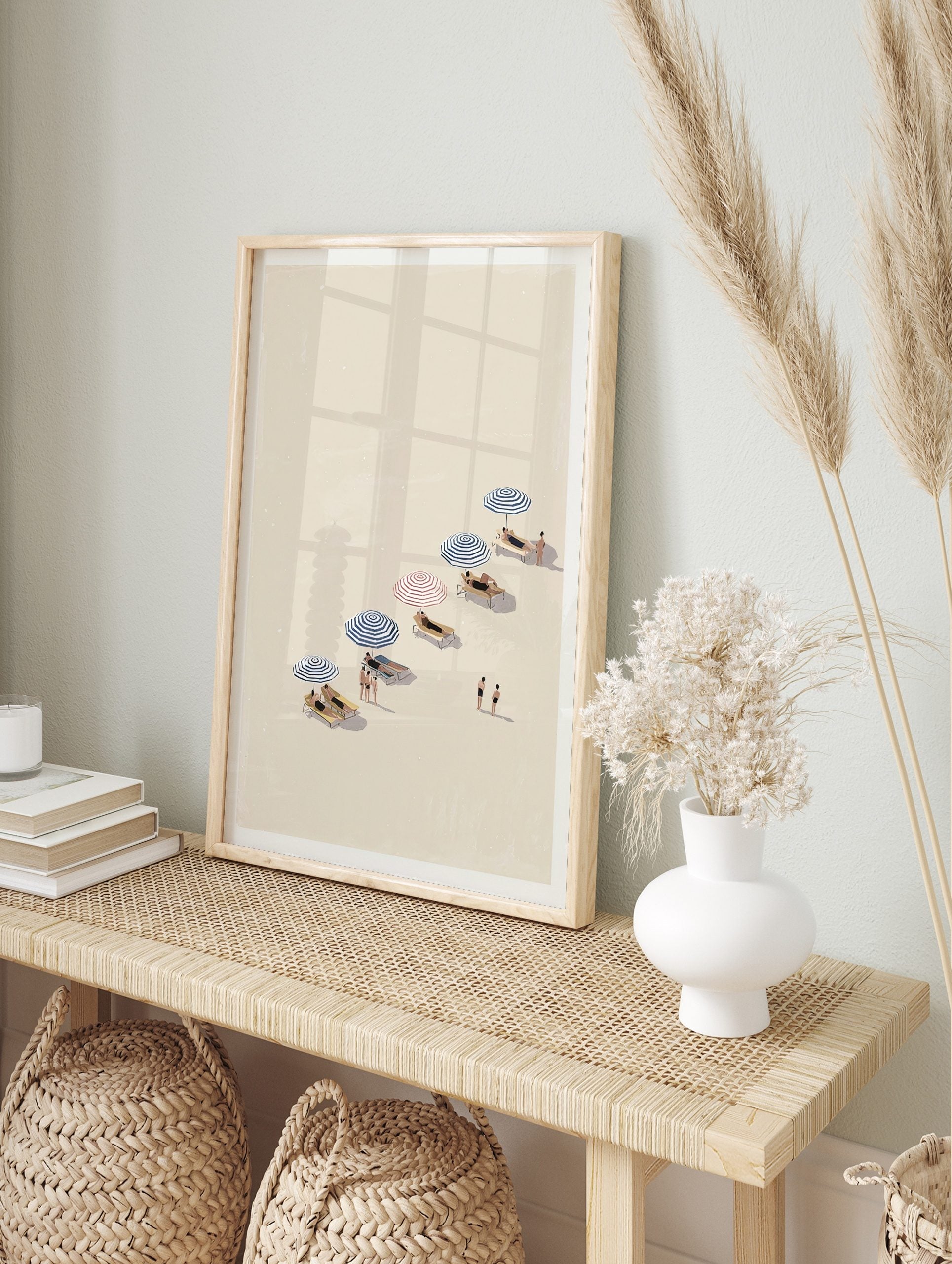Illustrative beach day wall art with people relaxing under blue and red striped umbrellas on a sandy shore. - Image 2