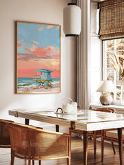 Painted lifeguard hut on a beach with a coral pink and blue sunset sky and ocean waves, in a styled room mockup