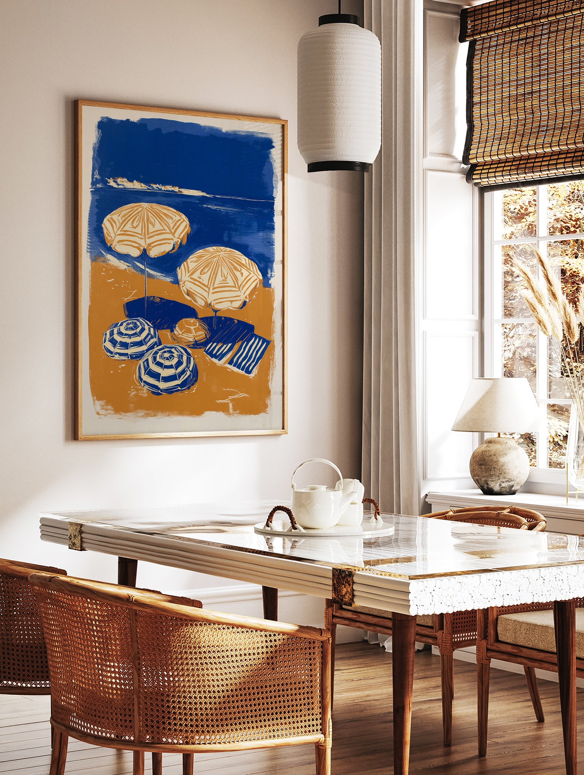 Blue and orange beach scene poster with two open umbrellas, two closed umbrellas, and a striped towel on the sand next to the ocean. - Image 2