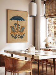 Illustrative beach scene with navy blue umbrella, striped deck chairs, and stylised blue botanical, in a styled room mockup