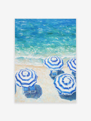 Blue and white striped beach umbrellas poster on a sandy beach next to turquoise ocean waves.