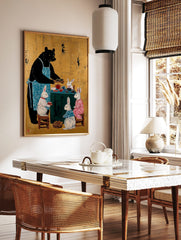 Black bear in blue apron serving tea to four white rabbits around a green table on a gold background, in a styled room mockup