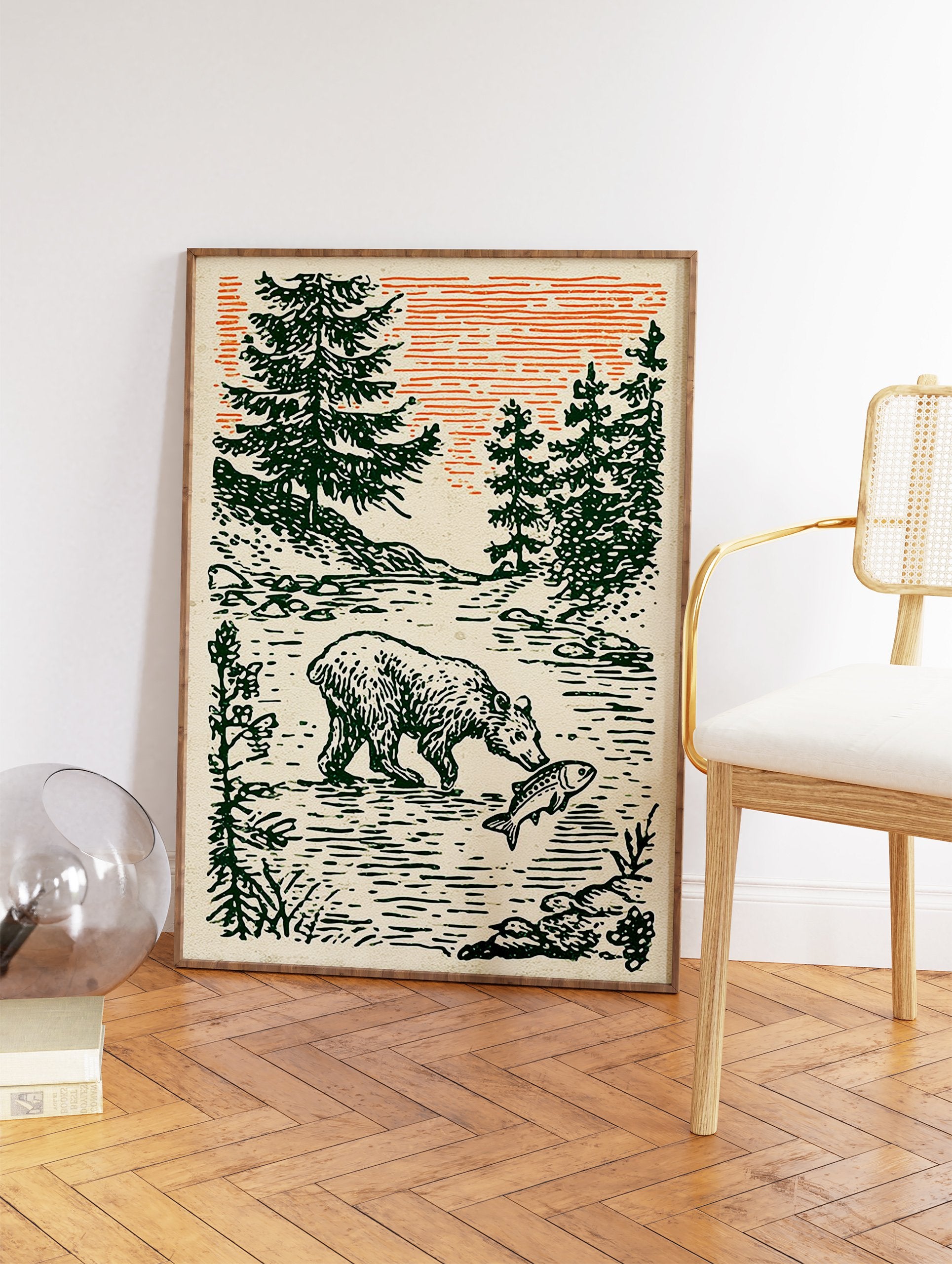 Illustrative art print of a bear catching a fish in a river, surrounded by green pine trees under an orange sky. - Image 2