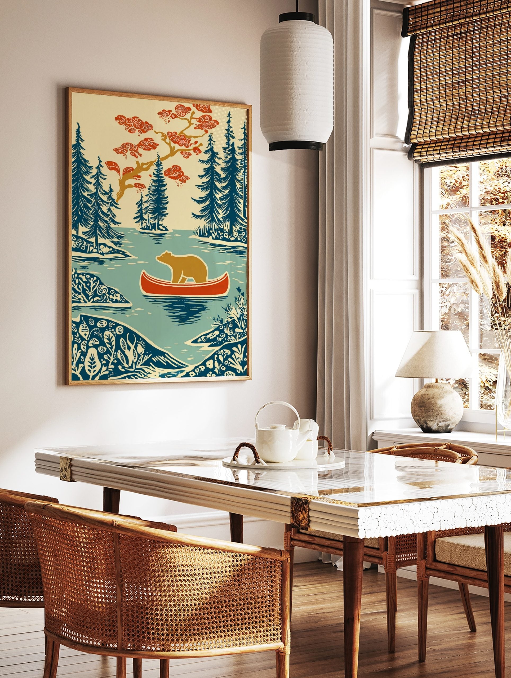 Woodcut style print of a brown bear in a red canoe on a lake, surrounded by blue evergreen trees, in a styled room mockup
