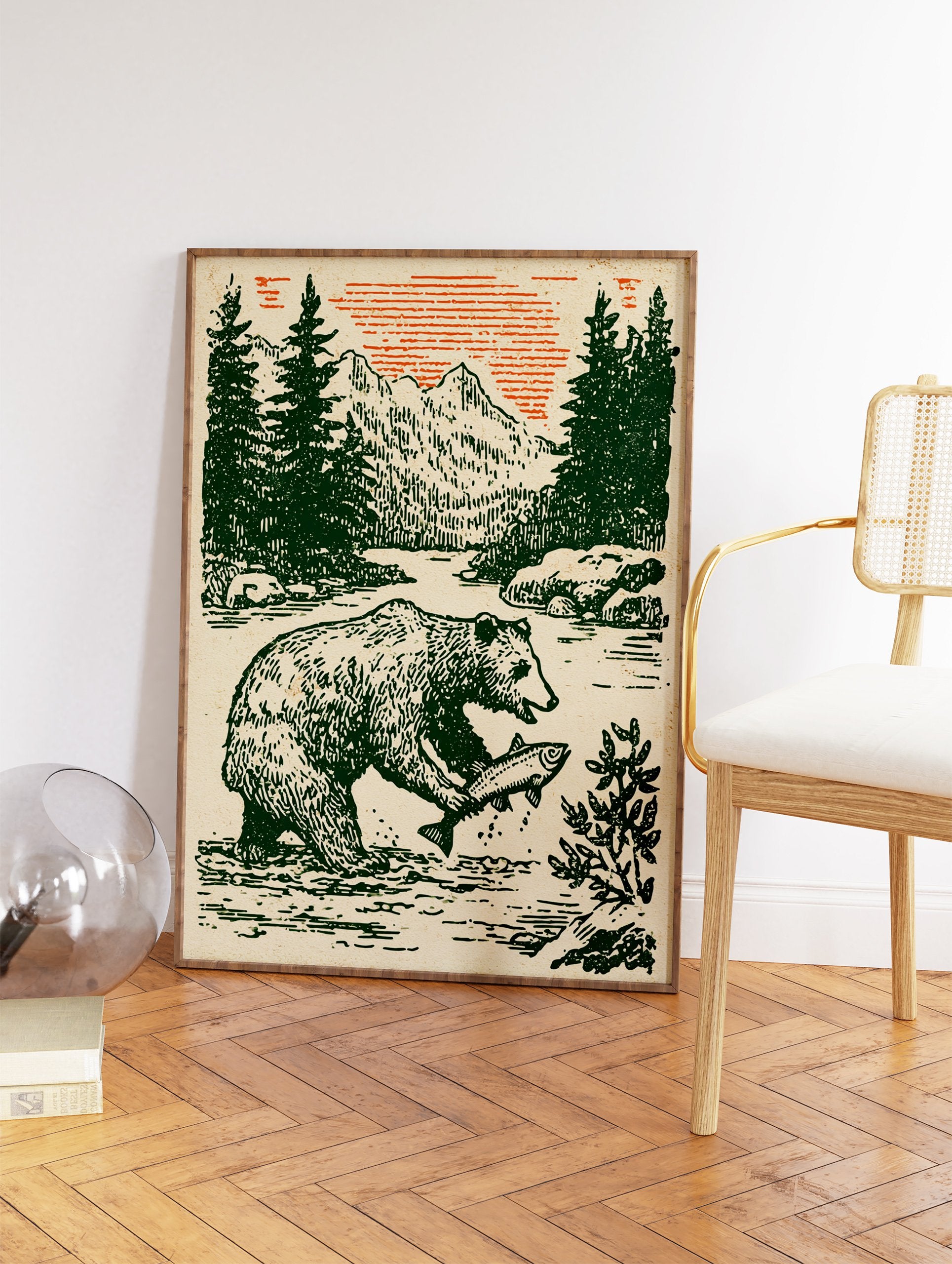 Vintage style illustration of a bear catching a fish in a river with pine trees, mountains, and an orange sky. Bear wall art. - Image 2