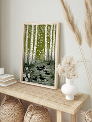 Green and white linocut print of birch trees, flying birds, ducks in a pond, and reeds with, in an alternate framed mockup