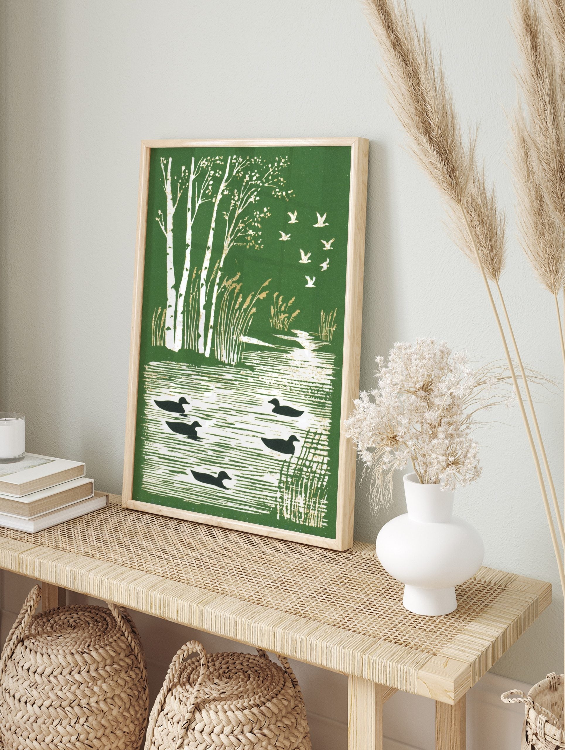 Illustrative green print with white birch trees, golden reeds, black ducks on water, and, in an alternate framed mockup