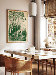 Green woodcut print of birch trees, tall grass, and five ducks swimming in water with two birds, in a styled room mockup