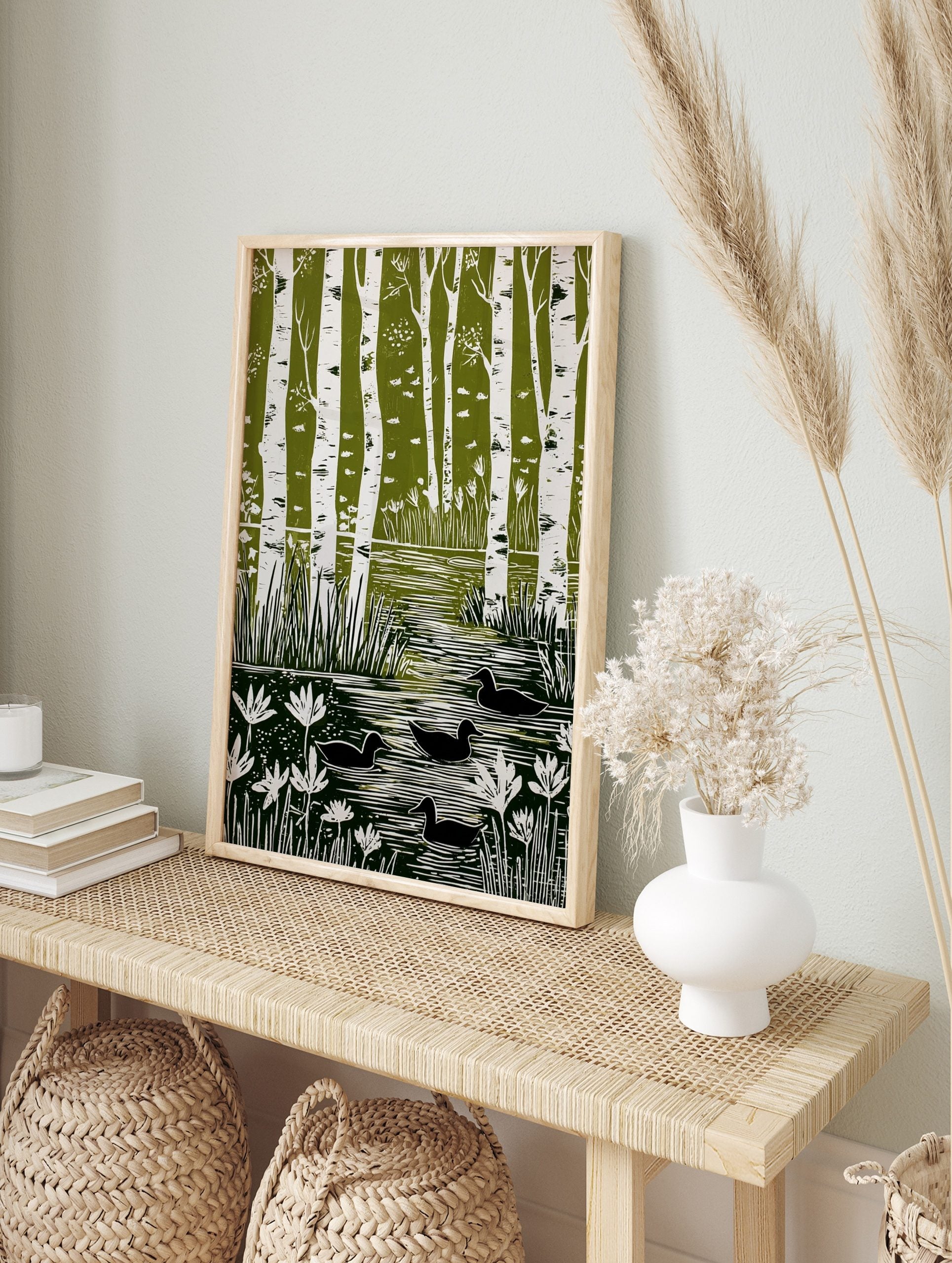 Green and white linocut style art print showing birch trees, a pond with reeds, water lilies, in an alternate framed mockup