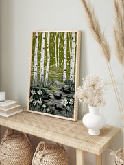 Green and white linocut style art print showing birch trees, a pond with reeds, water lilies, in an alternate framed mockup