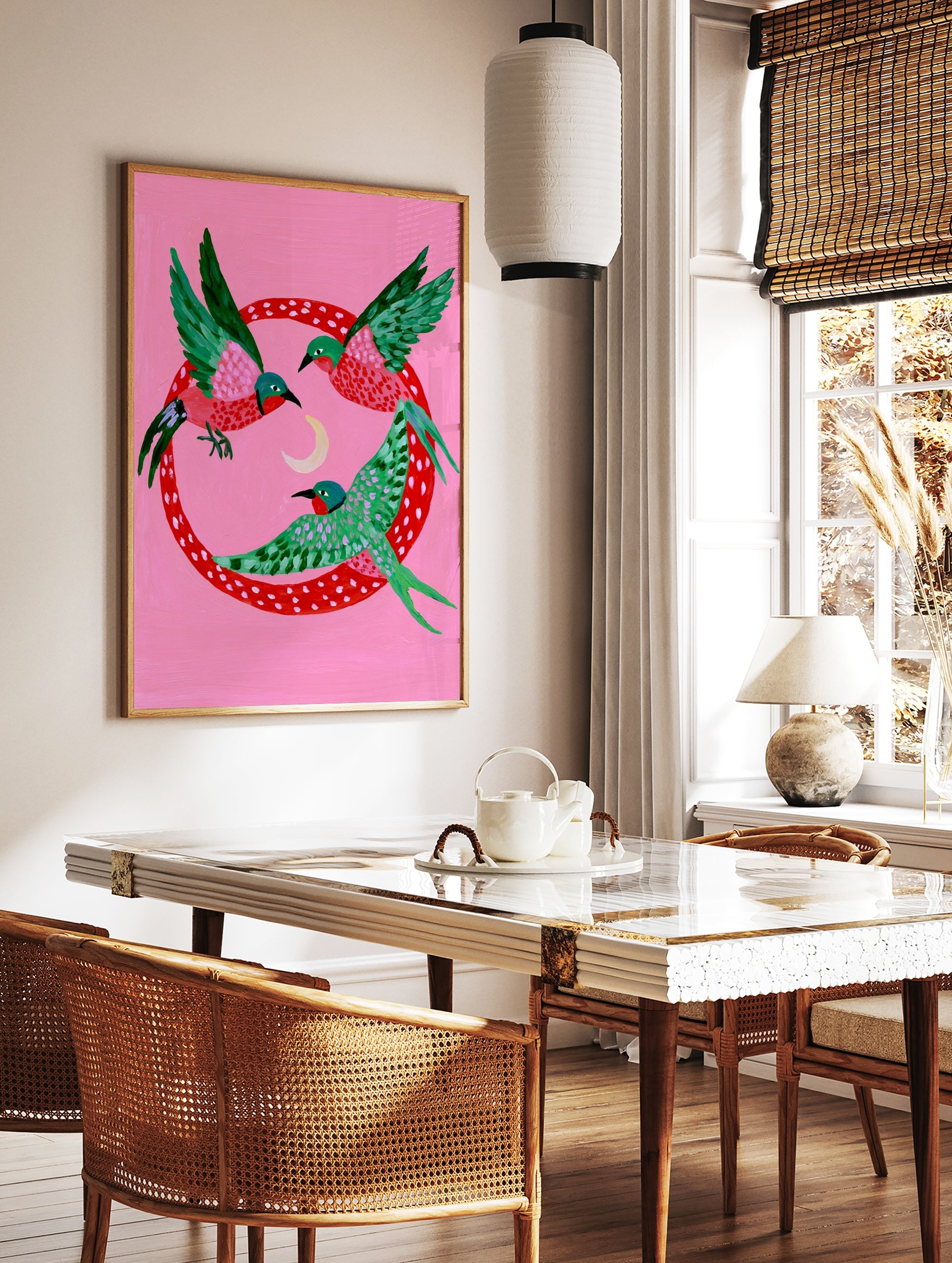 Three stylized birds with green and pink wings flying around a crescent moon inside a red polka-dot, in a styled room mockup