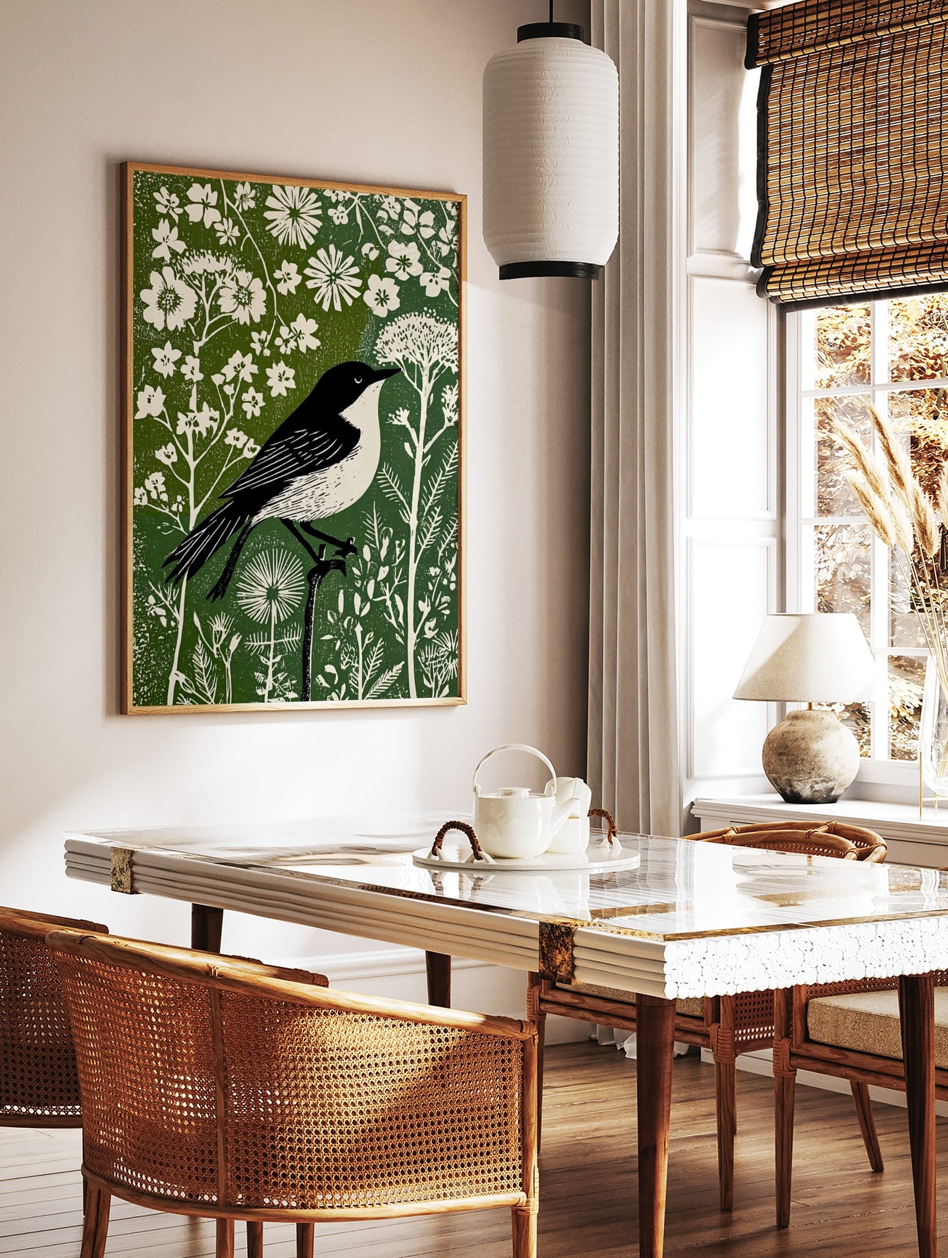 Black and white bird in linocut style perched on branch amidst white flowers and green foliage print, in a styled room mockup