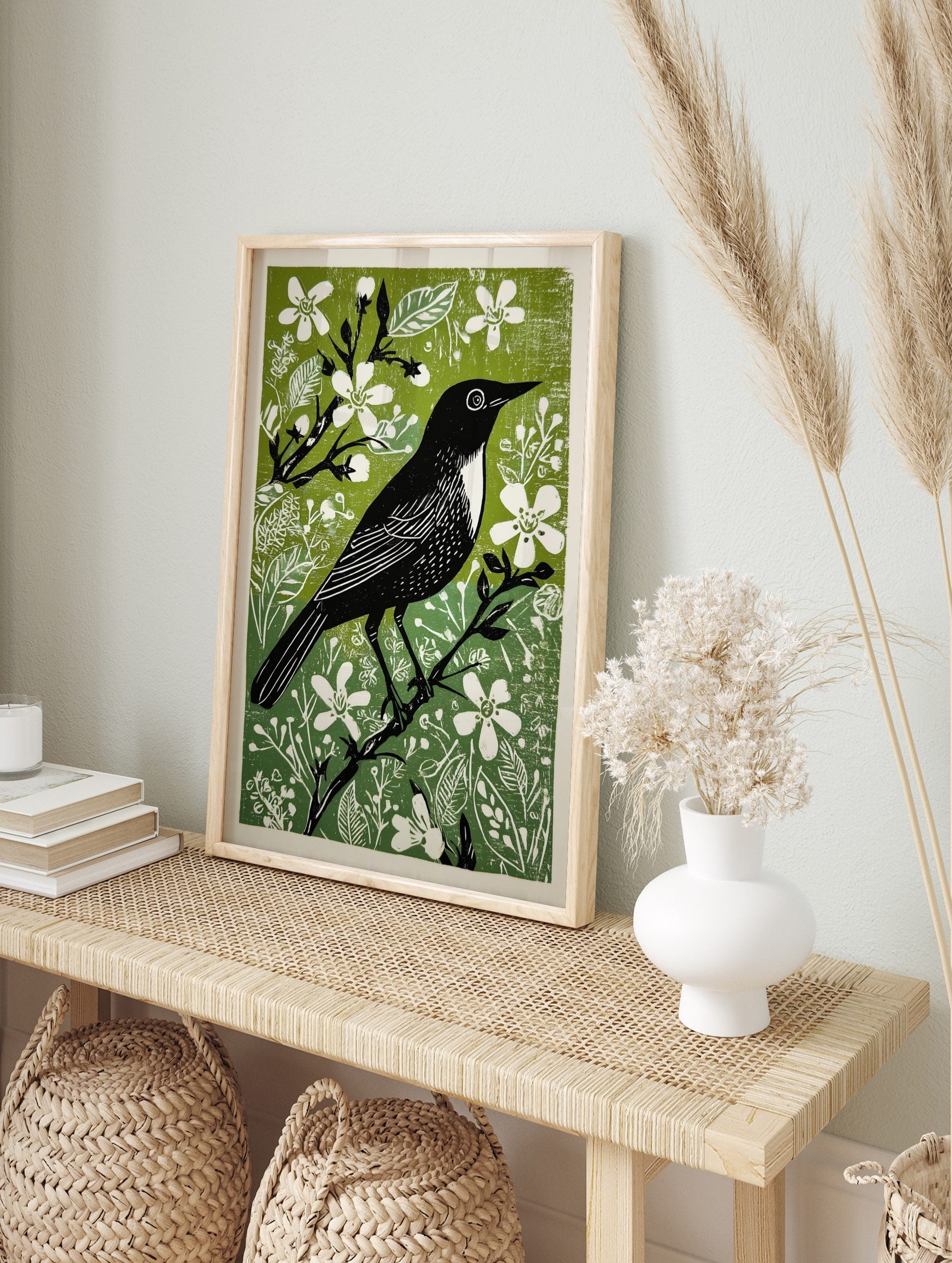Black bird with white chest and eye on a branch, surrounded by green foliage and white, in an alternate framed mockup