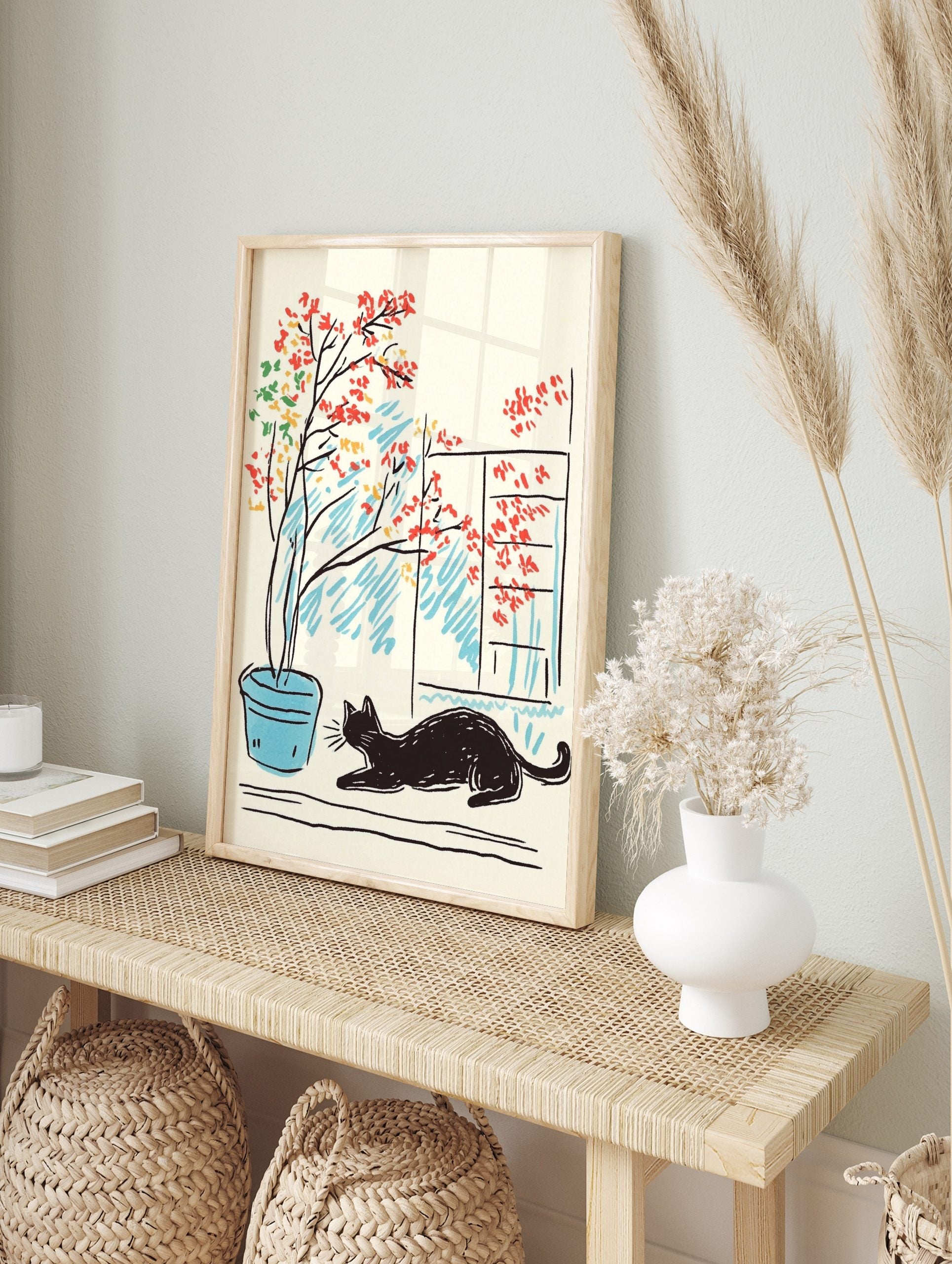 Illustrative print of a black cat lounging next to a potted plant with red, yellow, green, in an alternate framed mockup