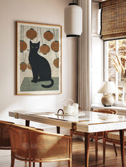 Black cat with green eyes sitting amidst hanging orange lanterns in Japanese woodblock style print, in a styled room mockup