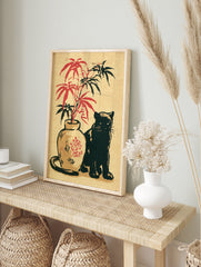 Japanese-inspired illustration of a black cat next to a vase with red and black bamboo leaves, in an alternate framed mockup