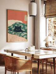 Illustrative print of a black cat with green eyes peeking from a green palm-leaf duvet against a, in a styled room mockup