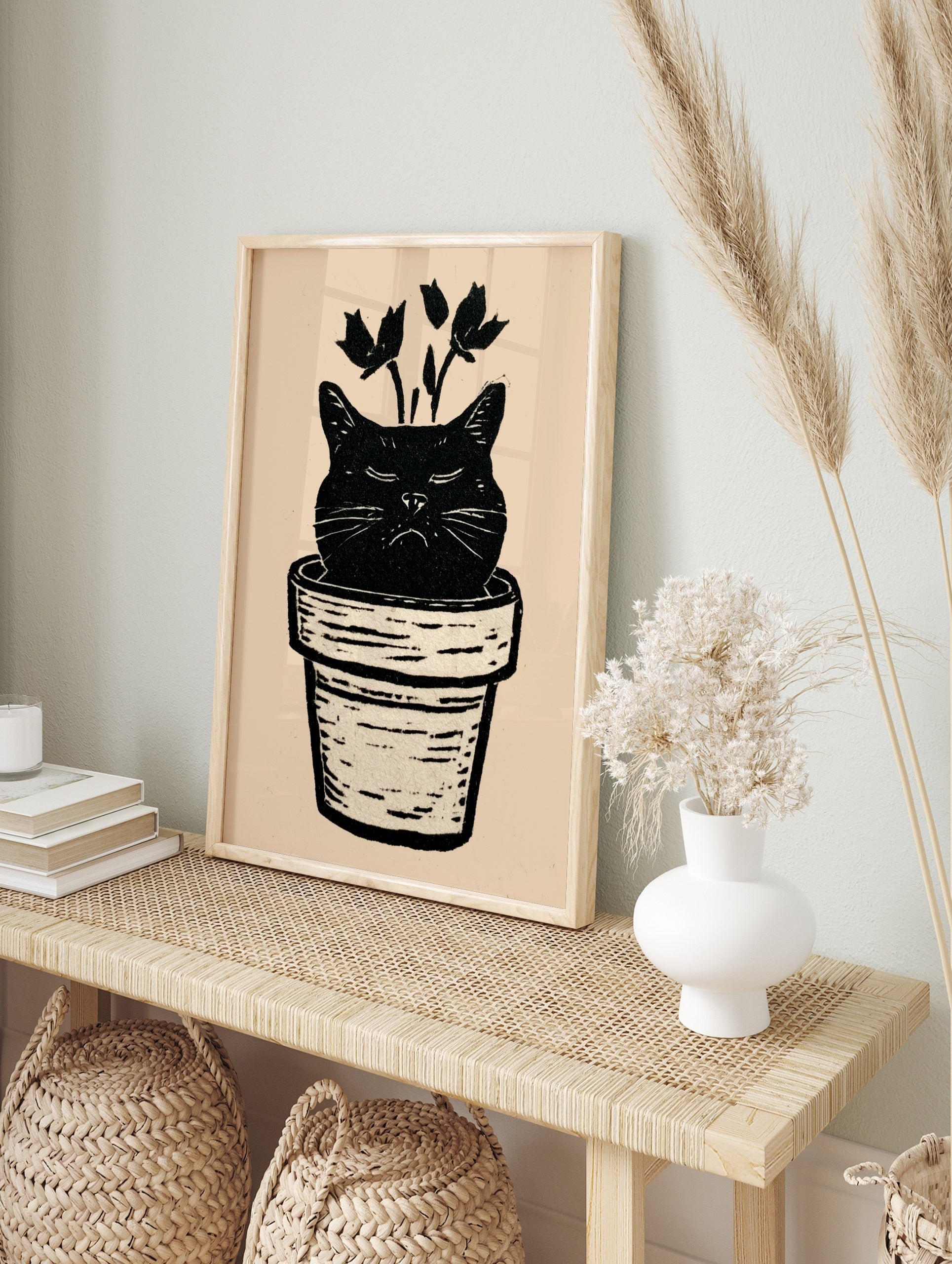 Black cat head in a plant pot with botanical stems, linocut style illustration on cream, in an alternate framed mockup