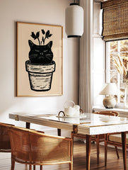 Black cat head in a plant pot with botanical stems, linocut style illustration on cream background, in a styled room mockup
