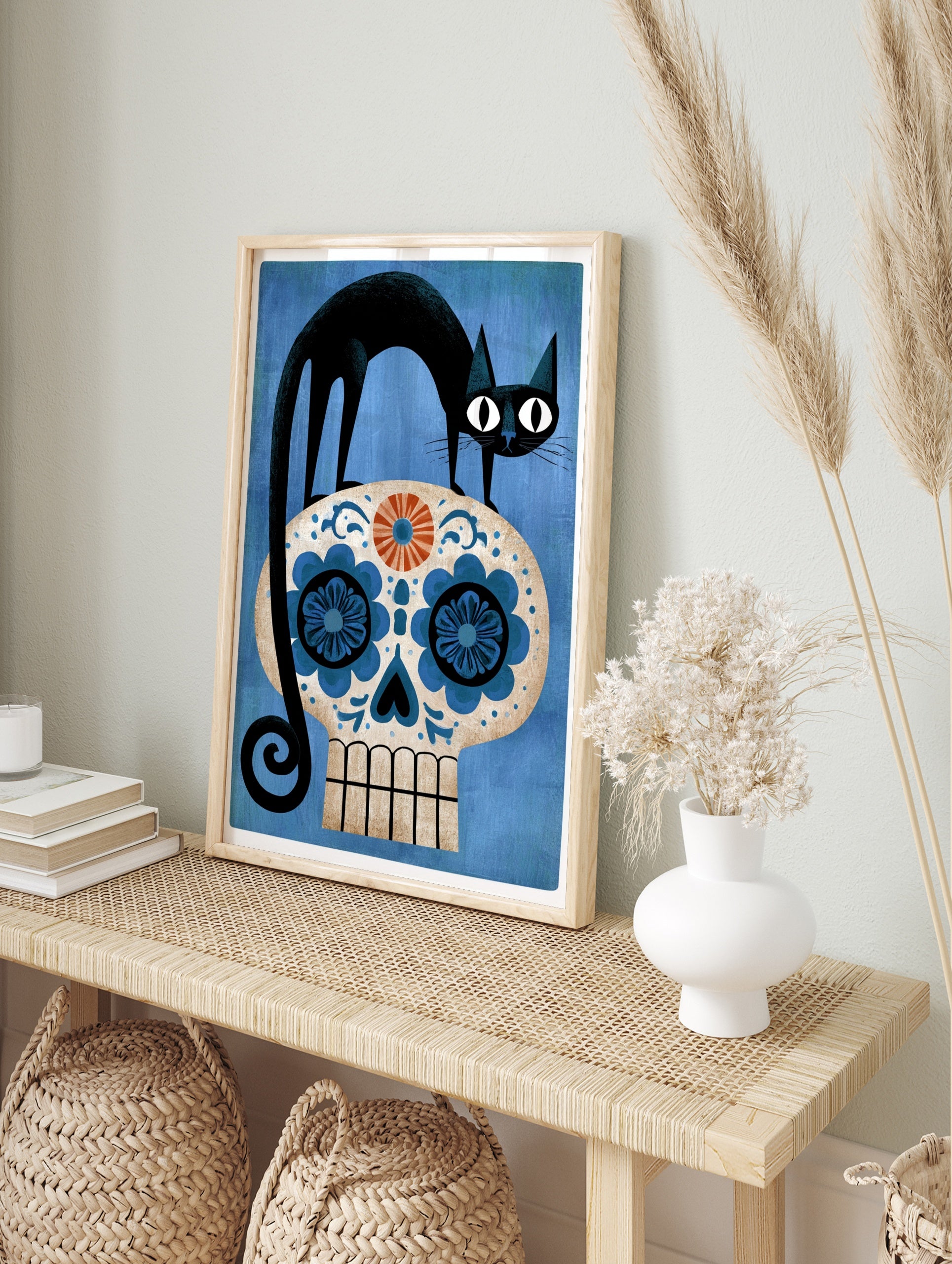 Black cat standing on a decorative blue and orange sugar skull floral illustration on a, in an alternate framed mockup