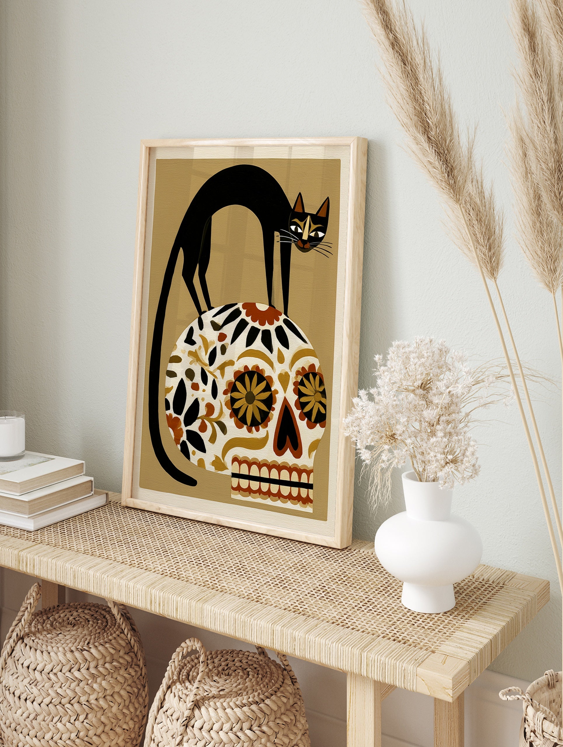 Black cat perched on a floral patterned Mexican sugar skull, illustrative art print on a, in an alternate framed mockup
