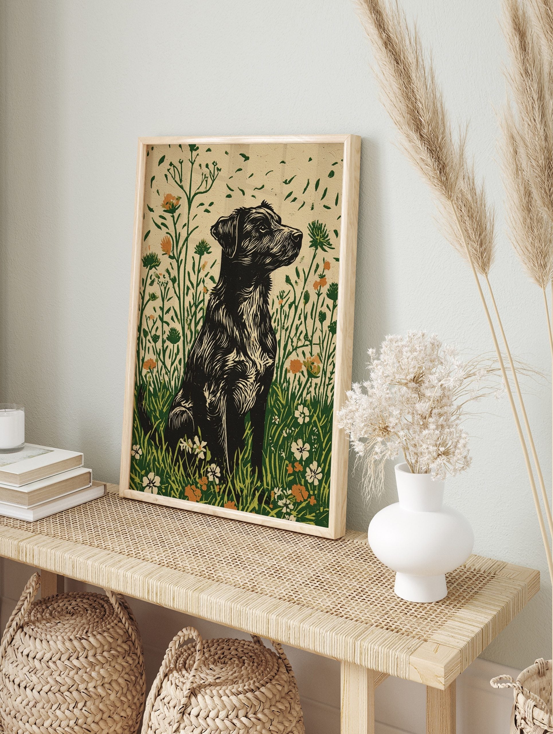 Black shaggy dog in linocut style sitting in a green and orange wildflower meadow art print, in an alternate framed mockup