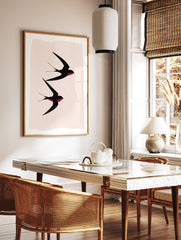 Black Swallows Wall Art print showing two minimalist black swallows with red details flying against a light pink background. - Image 2