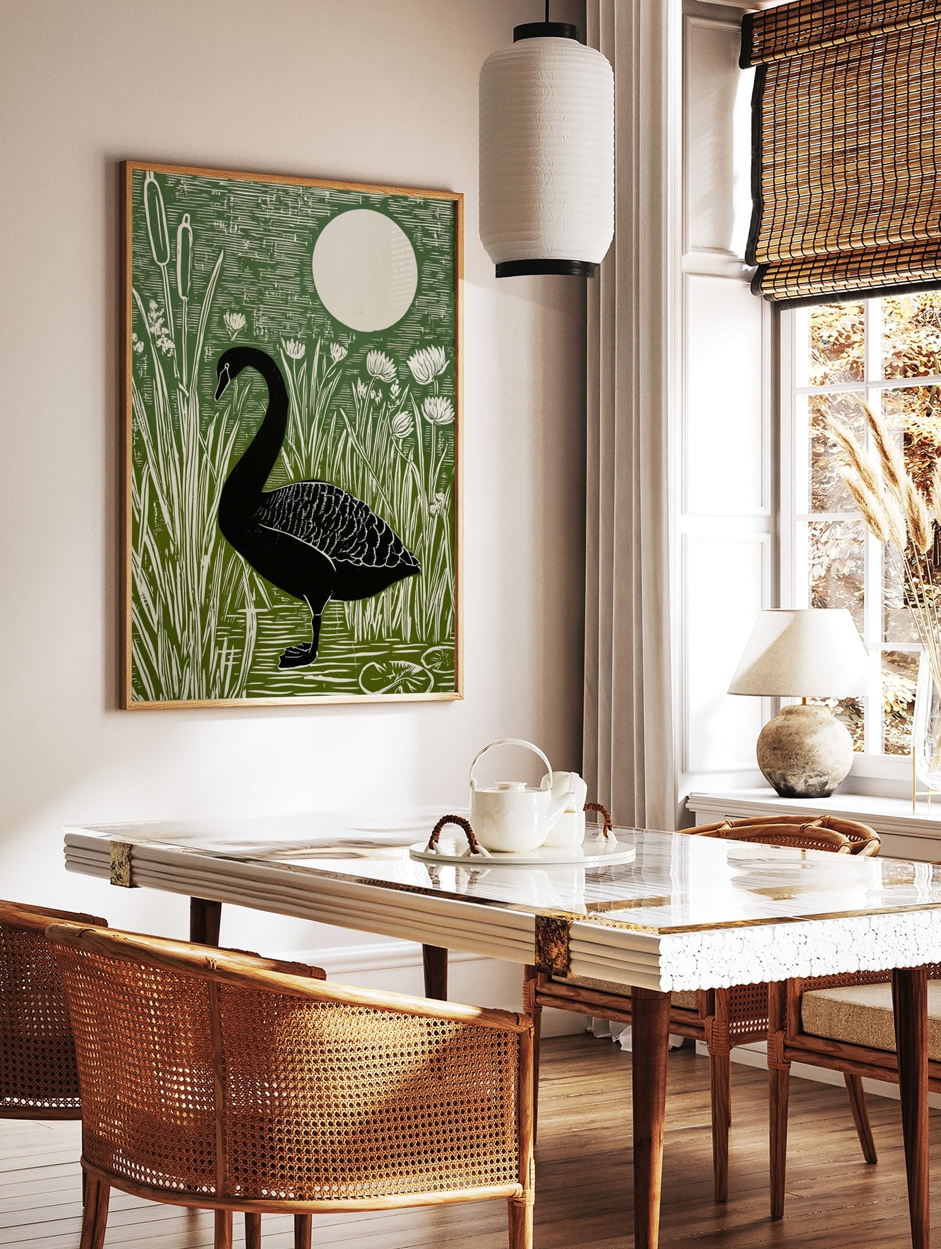 Black swan standing in water surrounded by green cattails and white flowers, with a large white moon, in a styled room mockup