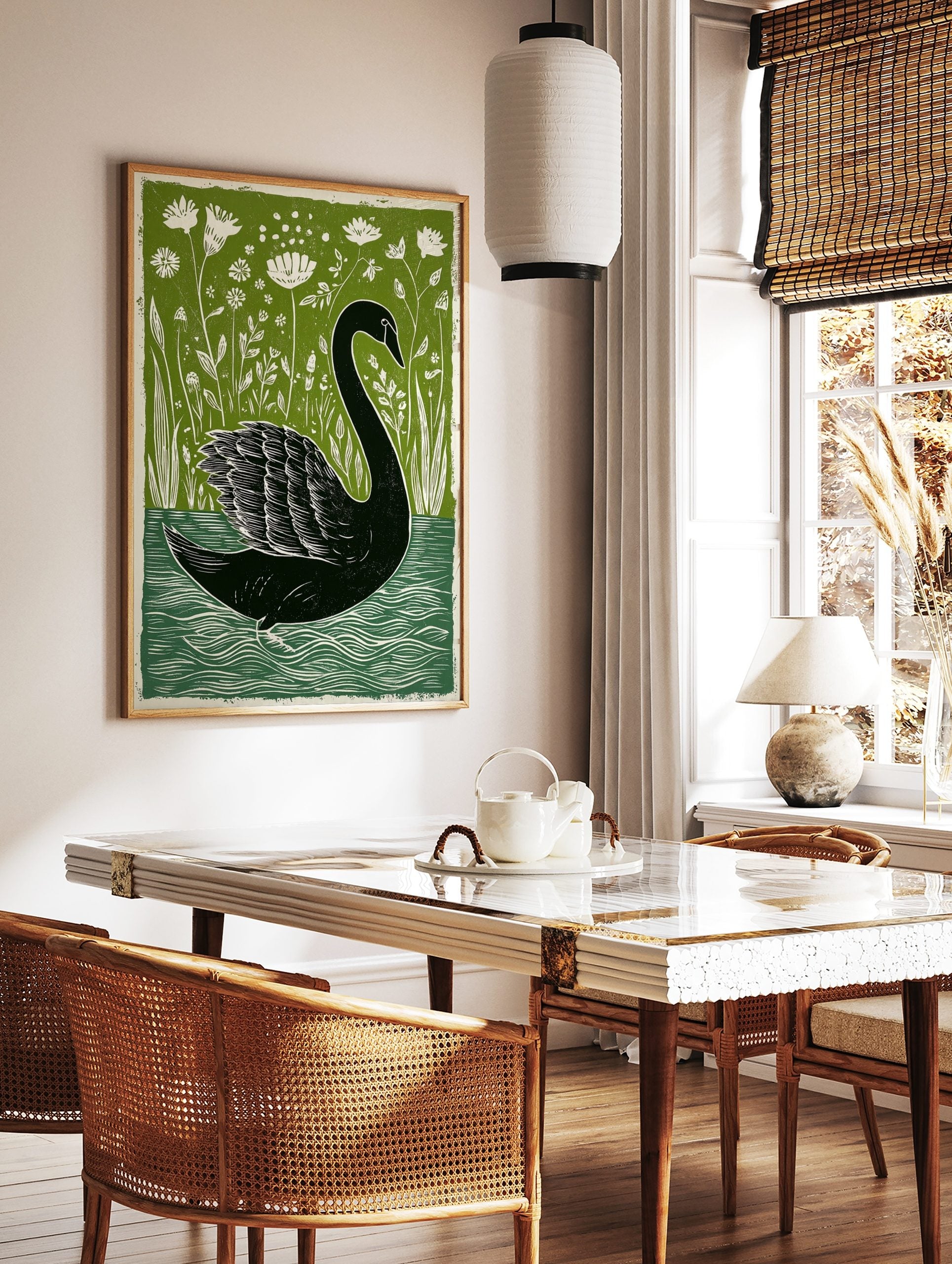 Black swan linocut print on water with green botanical foliage and white flowers in background, in a styled room mockup