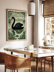 Black swan swimming in water with reeds and foliage, green linocut style print, in a styled room mockup