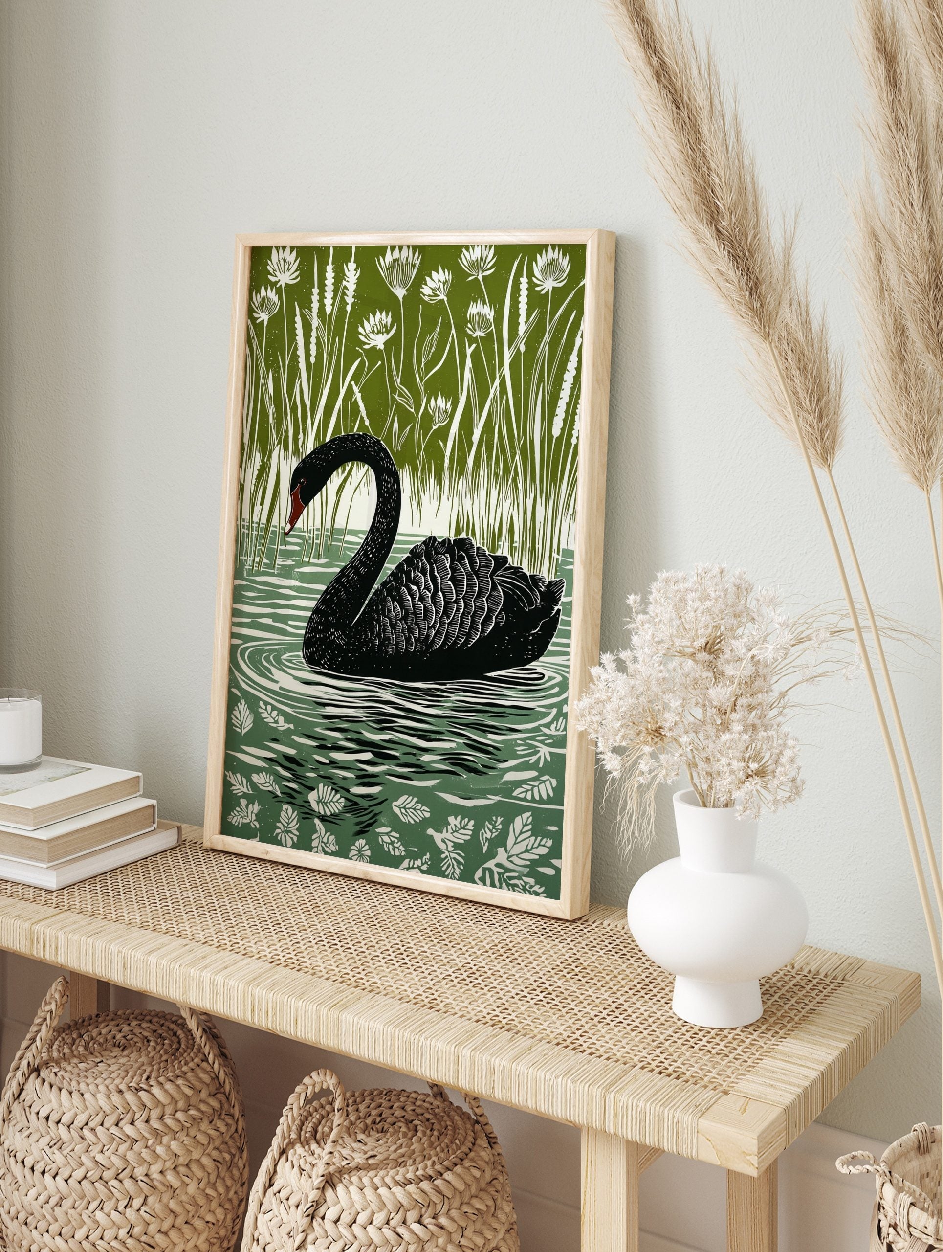 Black swan with red beak swimming in green water surrounded by white reeds and flowers, in an alternate framed mockup