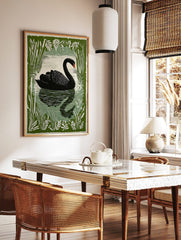 Illustrative black swan swimming on water, framed by green cattails and leaves, with a reflection, in a styled room mockup