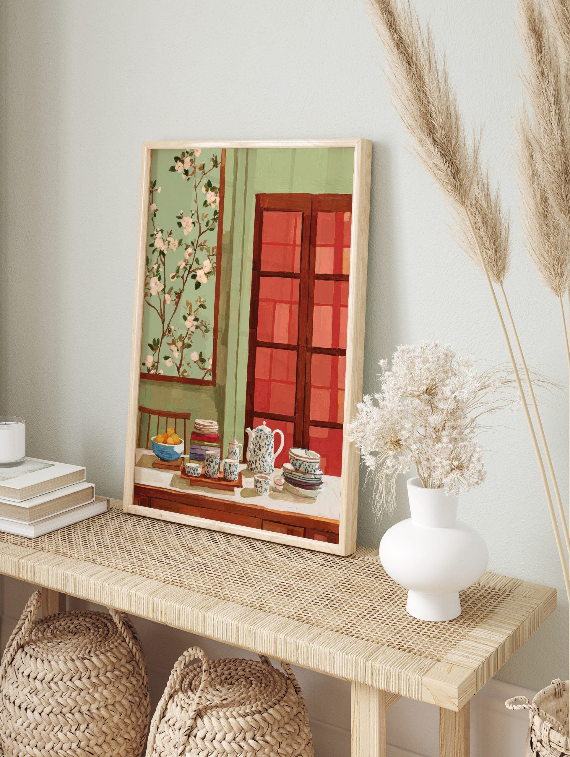 Still life painting of a teapot, tea cups, fruit bowl, and books on a table with blossom art, in an alternate framed mockup