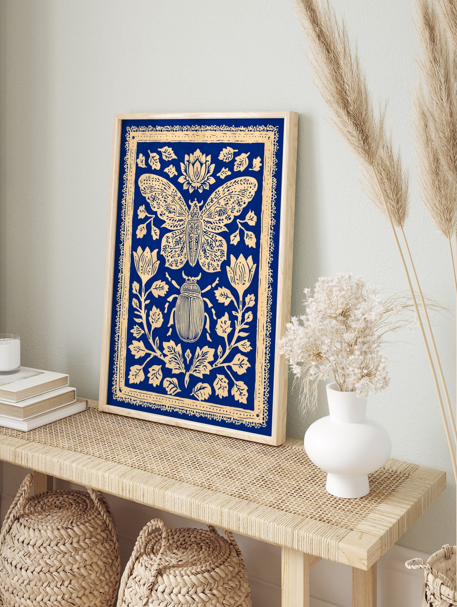 Blue and cream illustrative print of a moth and beetle surrounded by ornate botanical flowers, in an alternate framed mockup