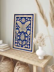 Blue and cream illustrative print of a moth and beetle surrounded by ornate botanical flowers, in an alternate framed mockup