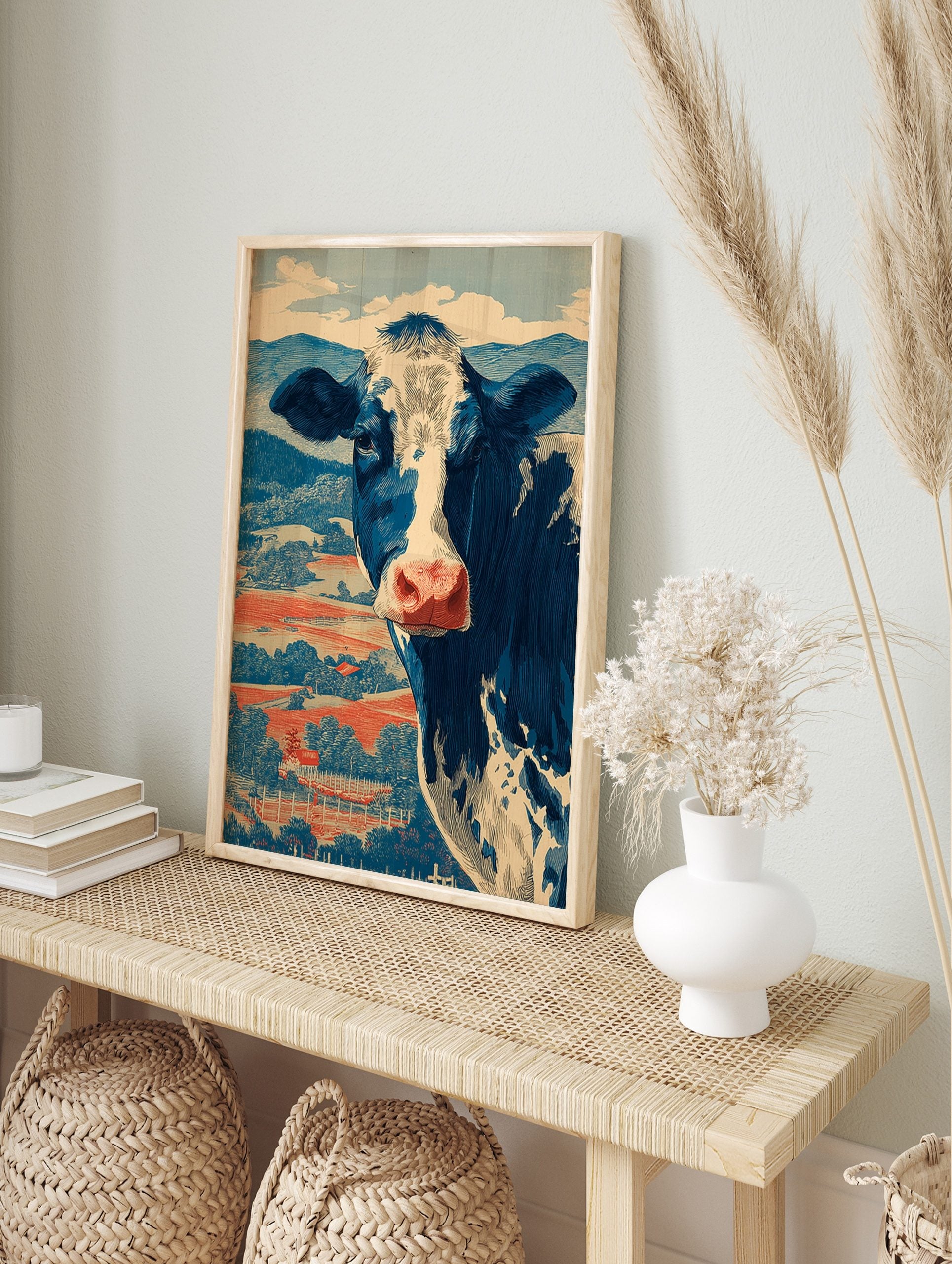 Blue and white Holstein cow illustration against red fields and blue hills, in a vintage, in an alternate framed mockup