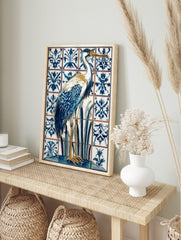 Blue and white heron bird illustration on ornate patterned tiles, with gold beak and legs, in an alternate framed mockup