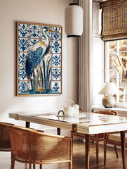 Blue and white heron bird illustration on ornate patterned tiles, with gold beak and legs, in a styled room mockup