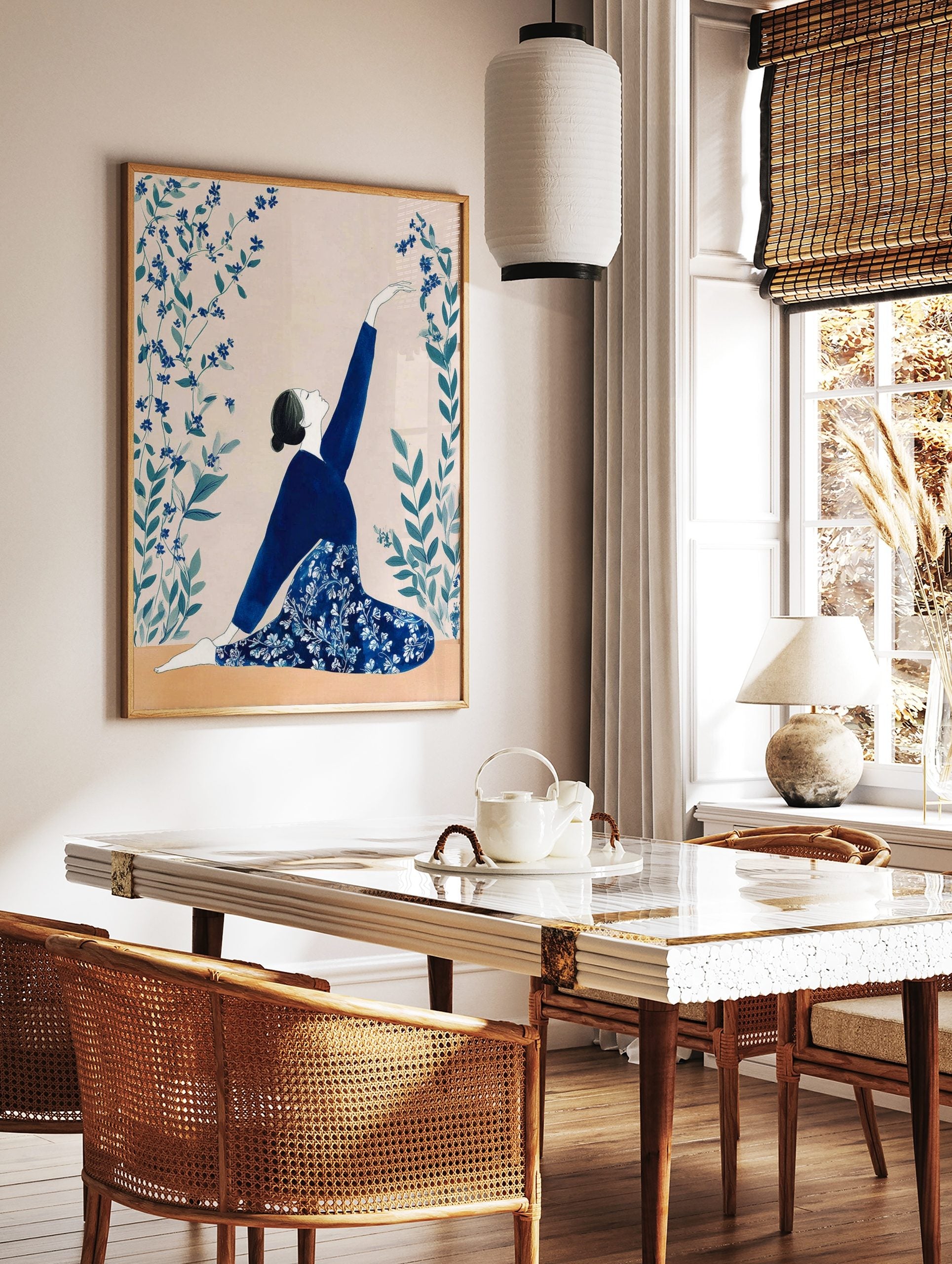 Illustrative print of a woman in a blue outfit in a kneeling yoga pose, reaching for blue flowers, in a styled room mockup