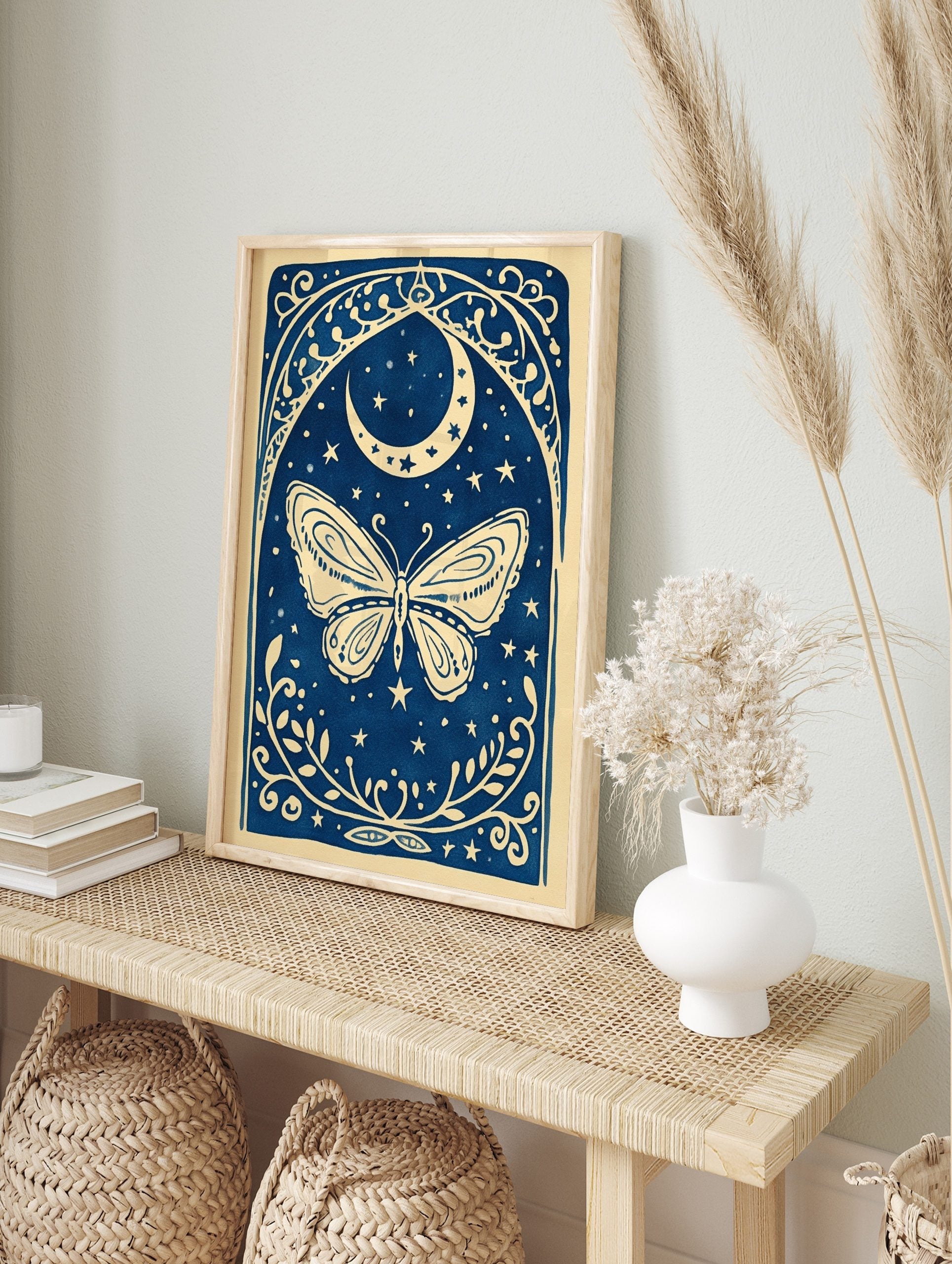 Illustrative blue and white butterfly with crescent moon, stars, and ornate botanical border, in an alternate framed mockup