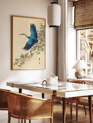 Japanese blue crane wall art print in flight with blue wings and long beak, flying past green leaves and red berries on a vine. - Image 2