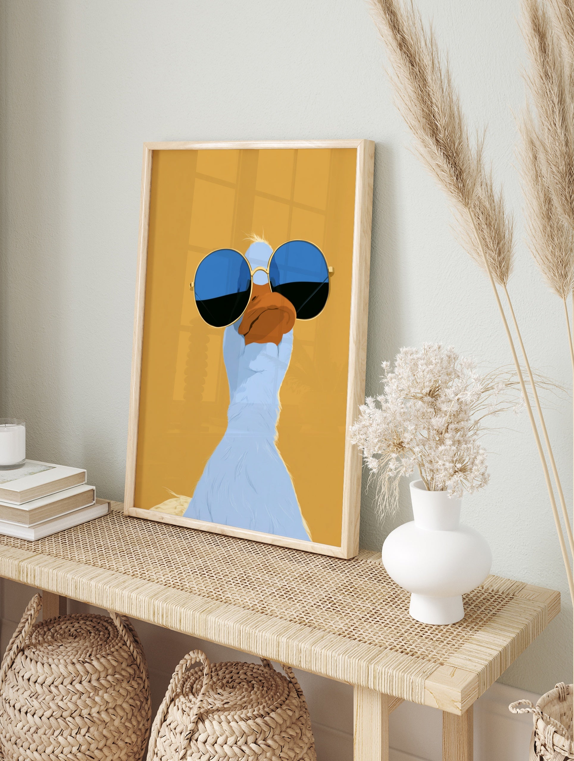 Stylized illustrative blue duck wearing round blue-tinted sunglasses on a solid mustard, in an alternate framed mockup
