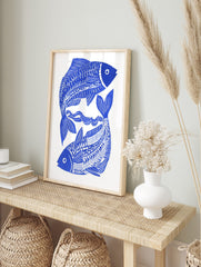 Blue and white illustrative print of two stylised fish intertwined with wavy lines on a white, in an alternate framed mockup