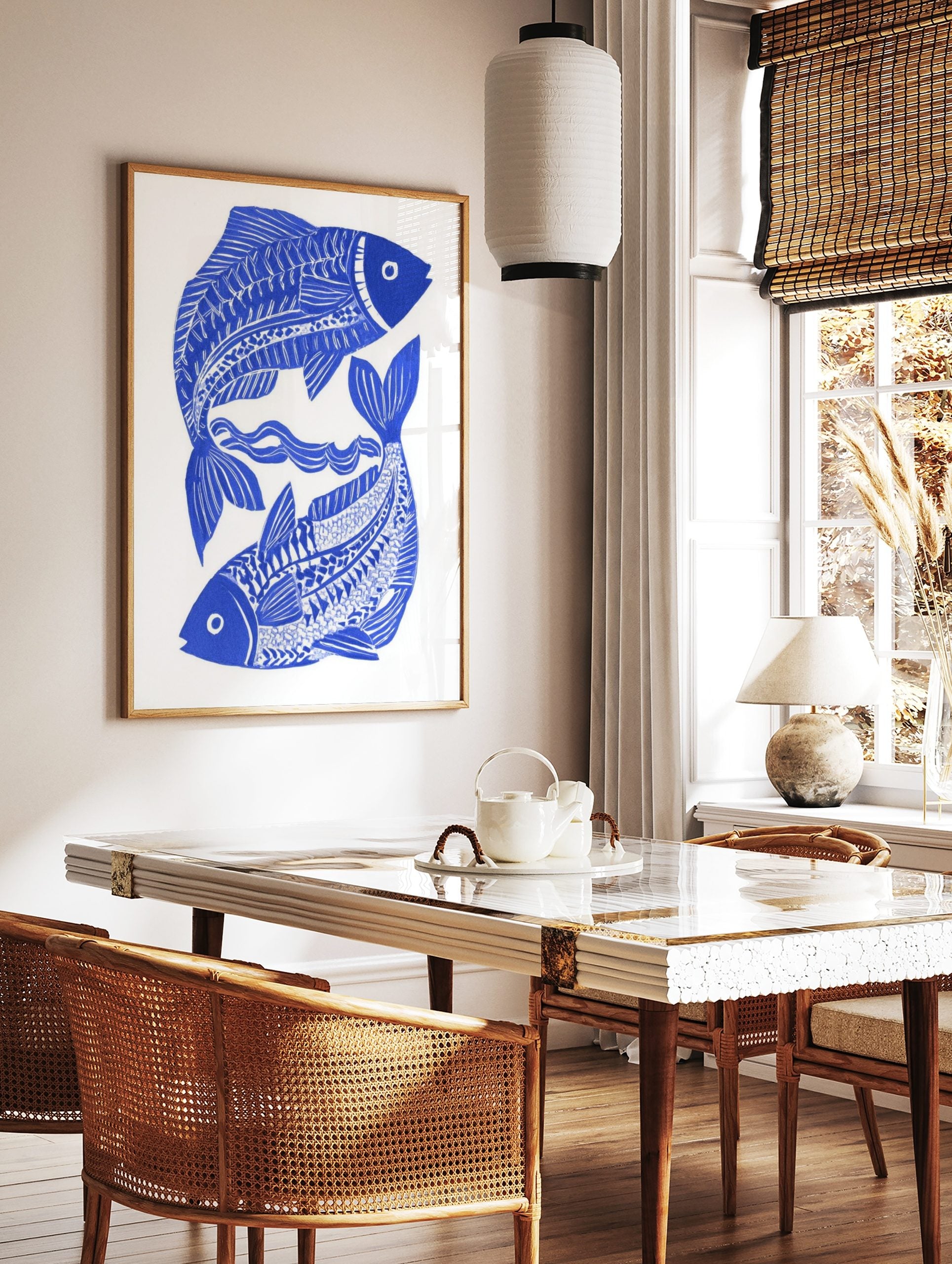 Blue and white illustrative print of two stylised fish intertwined with wavy lines on a white, in a styled room mockup