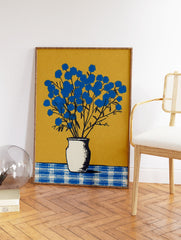 Blue flower wall art featuring a botanical illustration of vibrant blue flowers in a white vase on a checkered table against a gold background. - Image 2