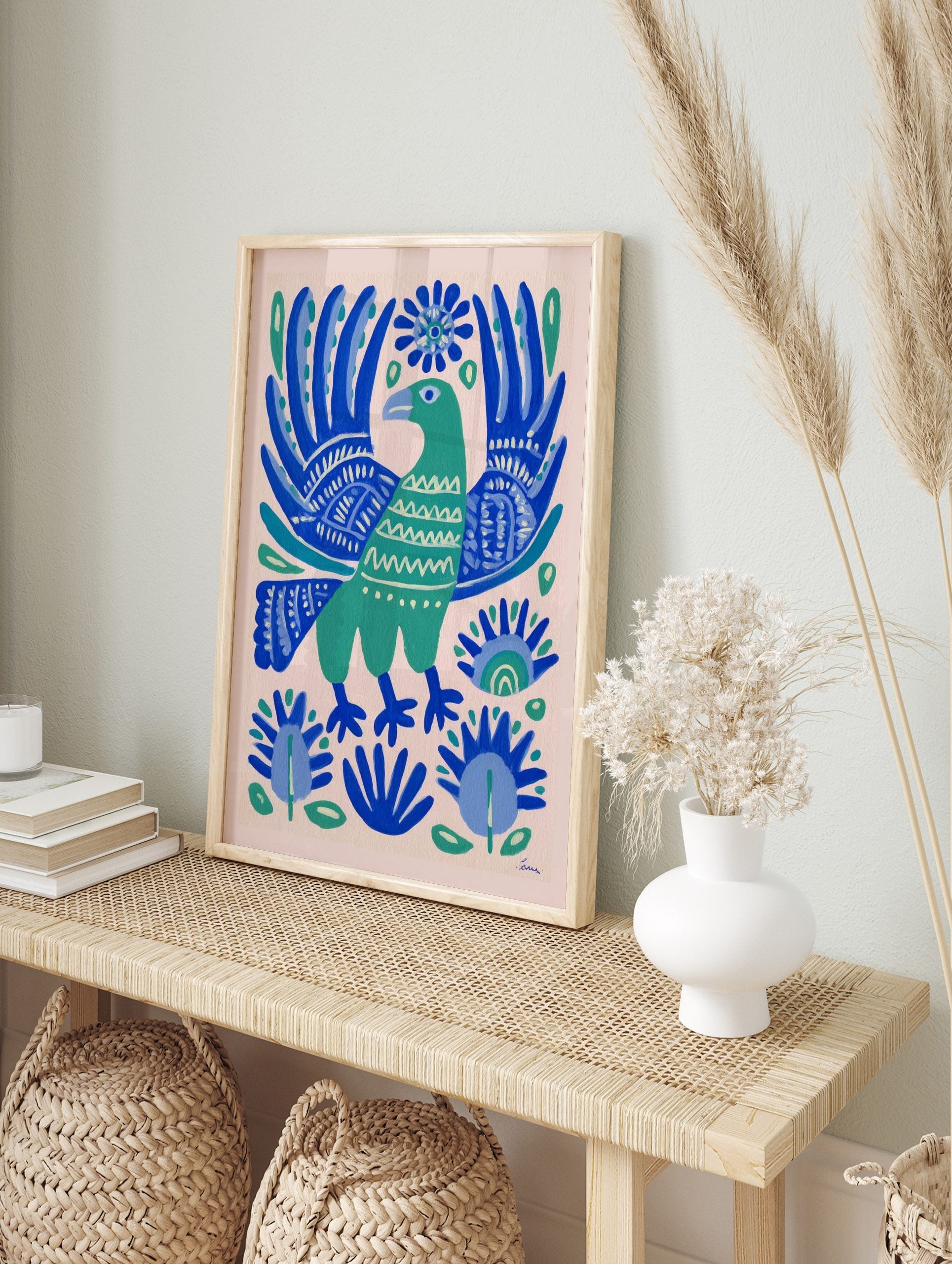 Green folk art bird with ornate blue wings and botanical patterns on a light background, in an alternate framed mockup